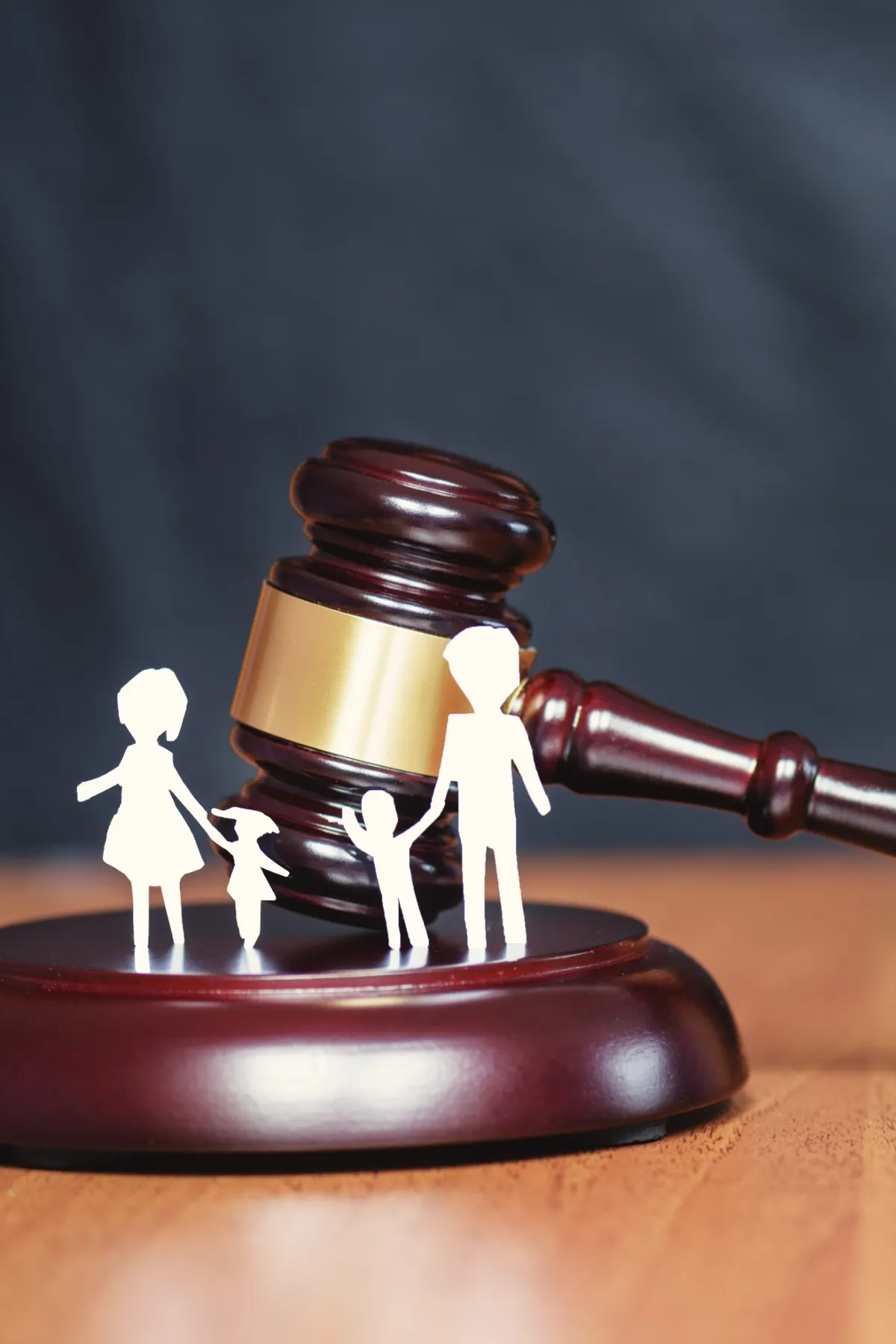 Image montrant un marteau de justice avec des silhouettes représentant une famille, illustrant la protection juridique des mineurs dans le cadre du droit familial.