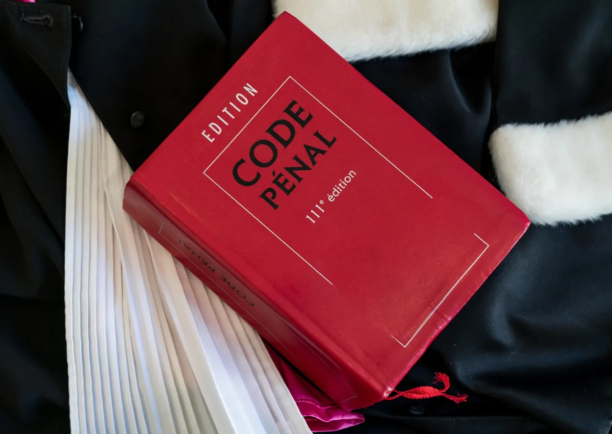 Code Pénal posé sur une robe d'avocat, symbolisant l'expertise en droit pénal.