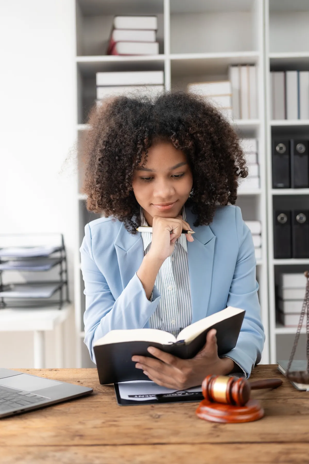 Une avocate concentrée lisant un ouvrage juridique dans un bureau, représentant l'apprentissage et la rigueur dans le domaine du droit.